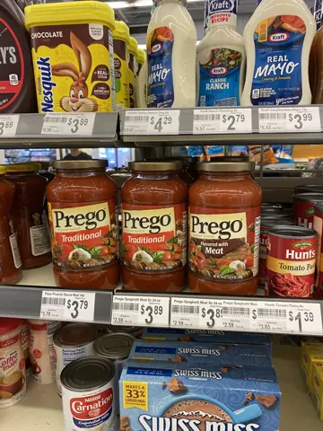 Grocery shelf stacked with jars of pasta sauce and mayonnaise
