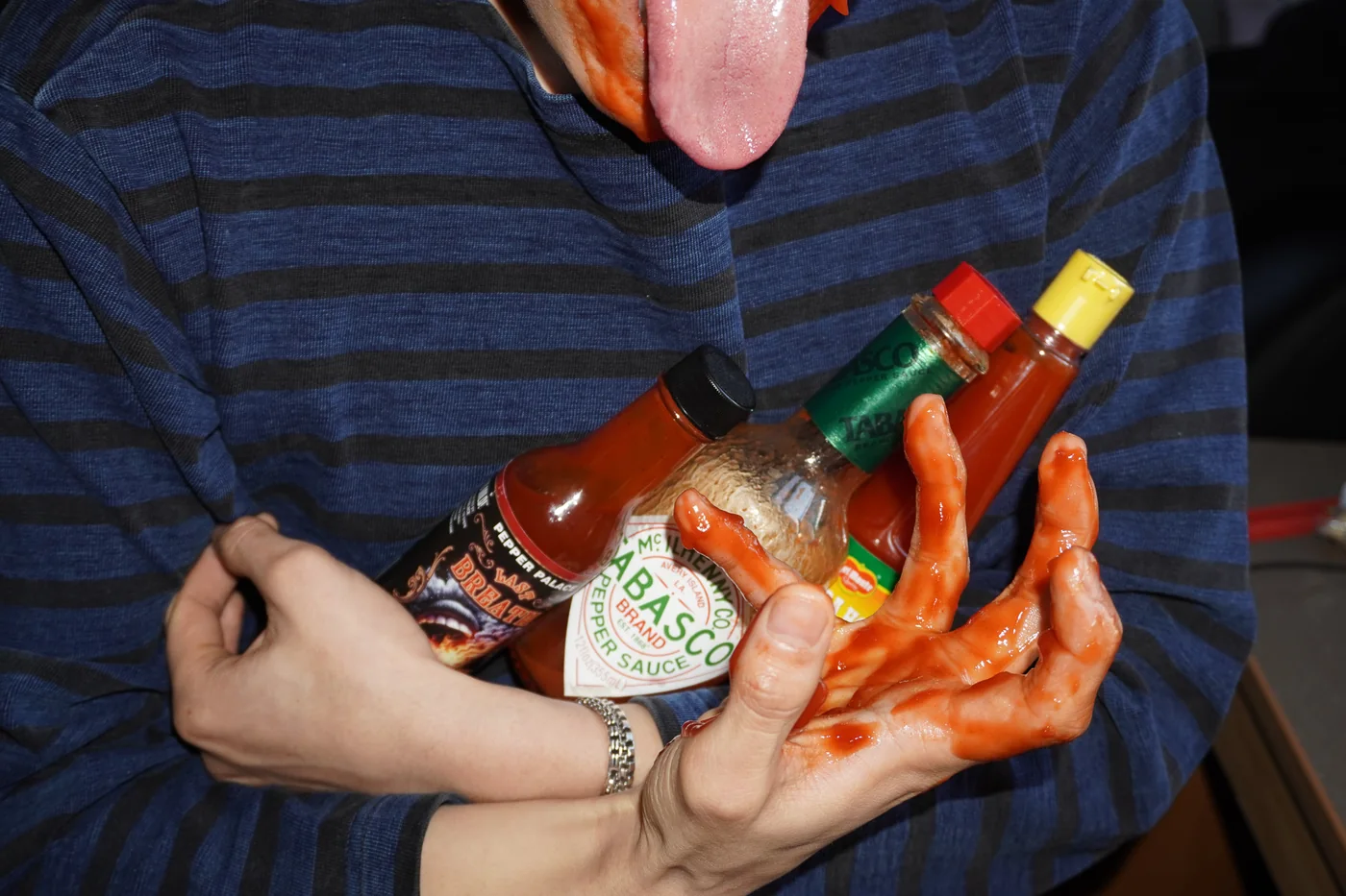 Tipping a sauce bottle straight into the mouth in front of a sauce shelf