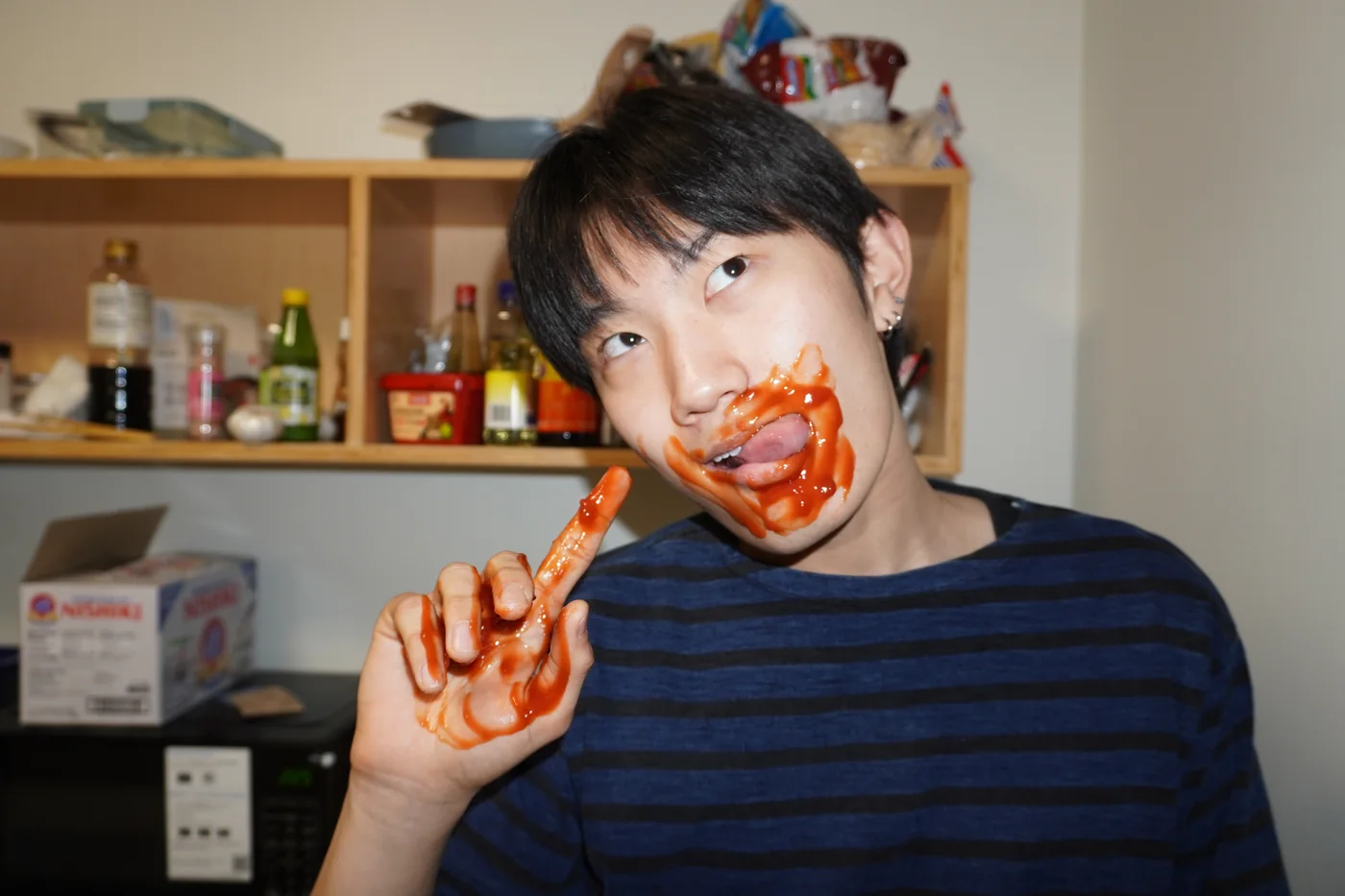 Sauce around the mouth, holding a hot sauce bottle
